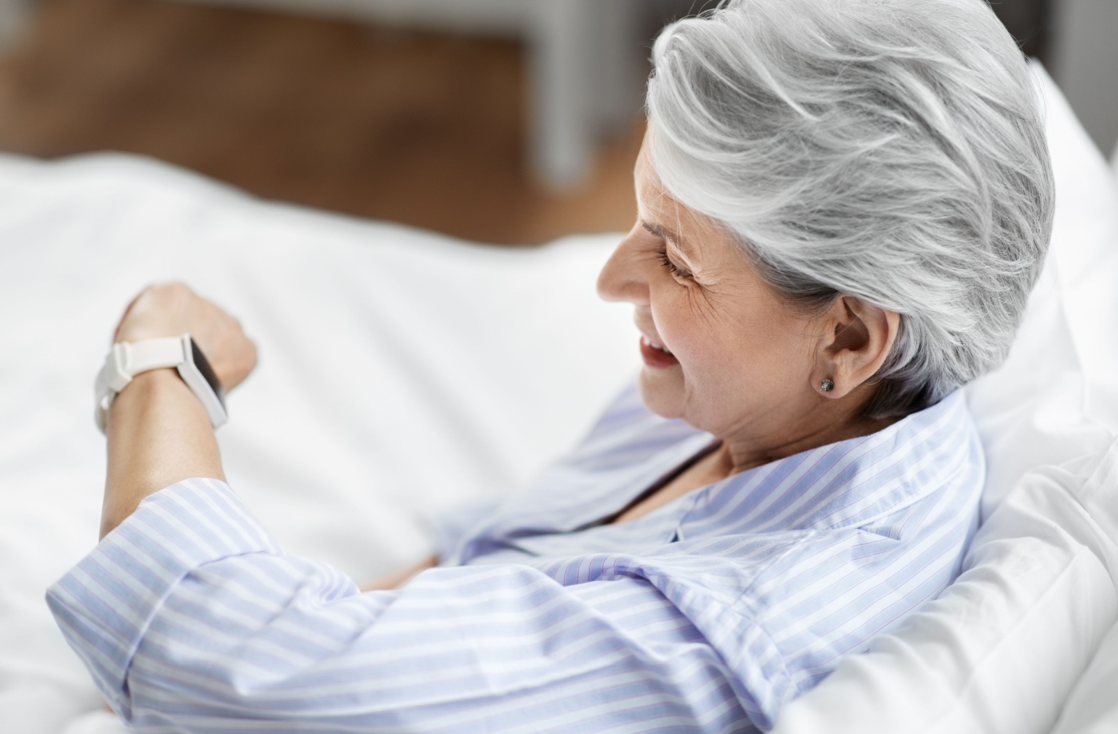 An older adult woman looking at her smartwatch to monitor her vitals.
