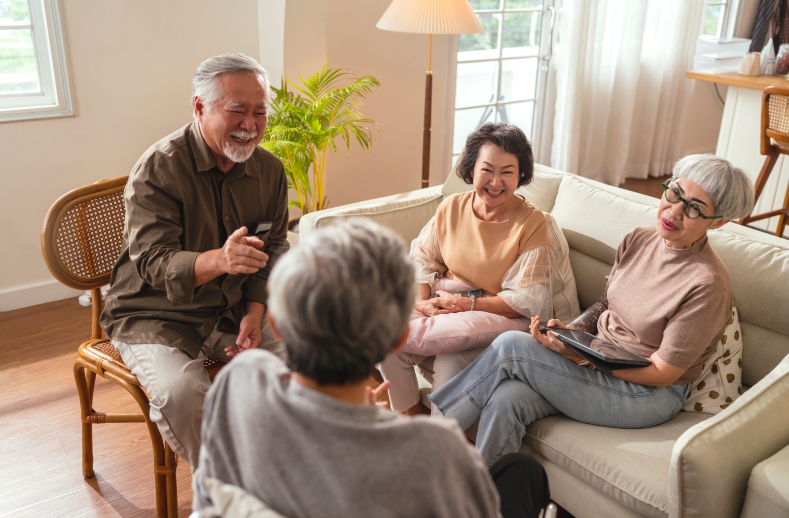 A group of older adults having fun while playing a trivia game on a tablet.
