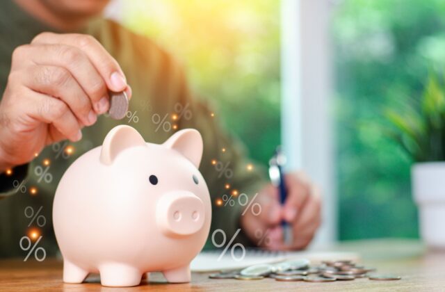 A person placing coins in a piggy bank to save for retirement planning.