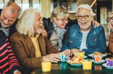 A group of seniors enjoying a lively conversation over coffee, sharing smiles and connection in a warm and welcoming environment.