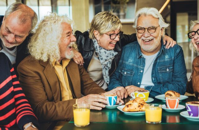 A group of seniors enjoying a lively conversation over coffee, sharing smiles and connection in a warm and welcoming environment.